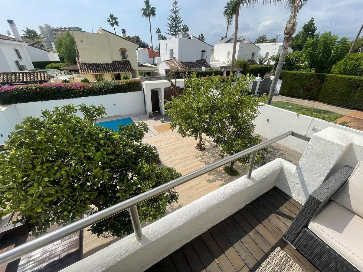 Balcony view of a villa with pool, trees, and outdoor seating area
