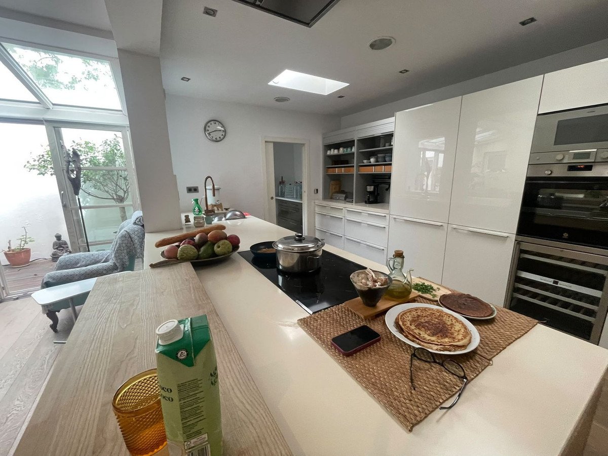 Modern kitchen with island, built-in appliances, and large windows showing outdoor view