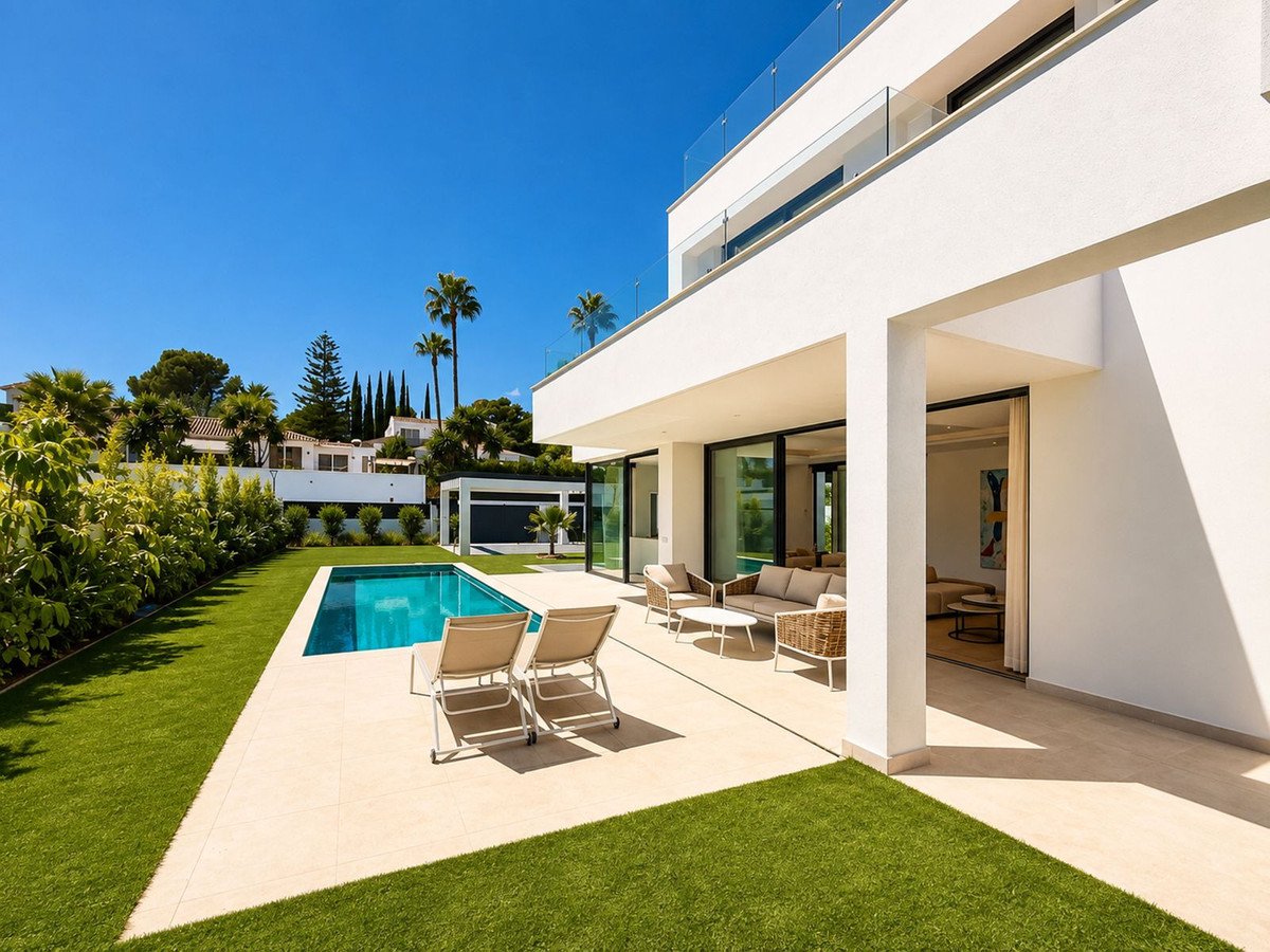 Modern villa with a swimming pool, lounge chairs, and outdoor seating area on a sunny day.