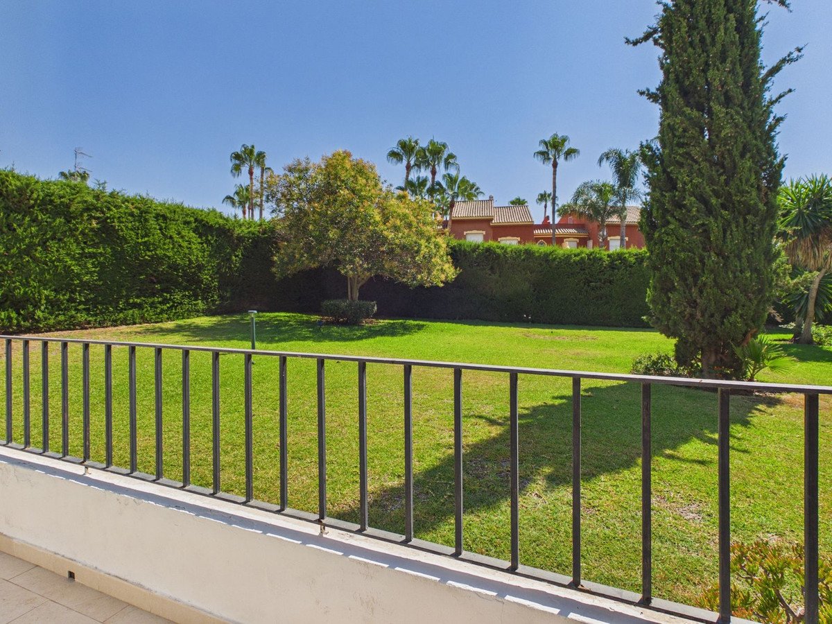 Balcony overlooking green lawns with palm trees and a hedge