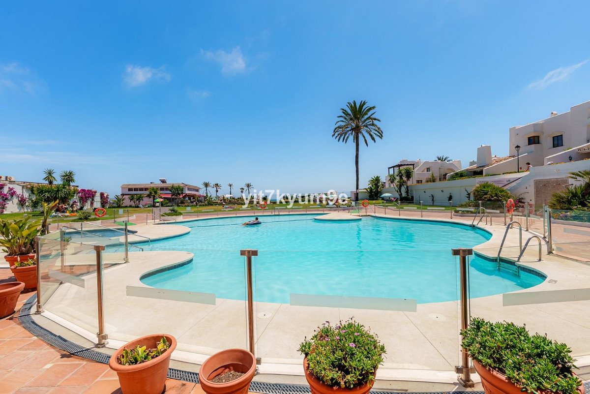 Large swimming pool with palm trees and surrounding buildings under a clear blue sky
