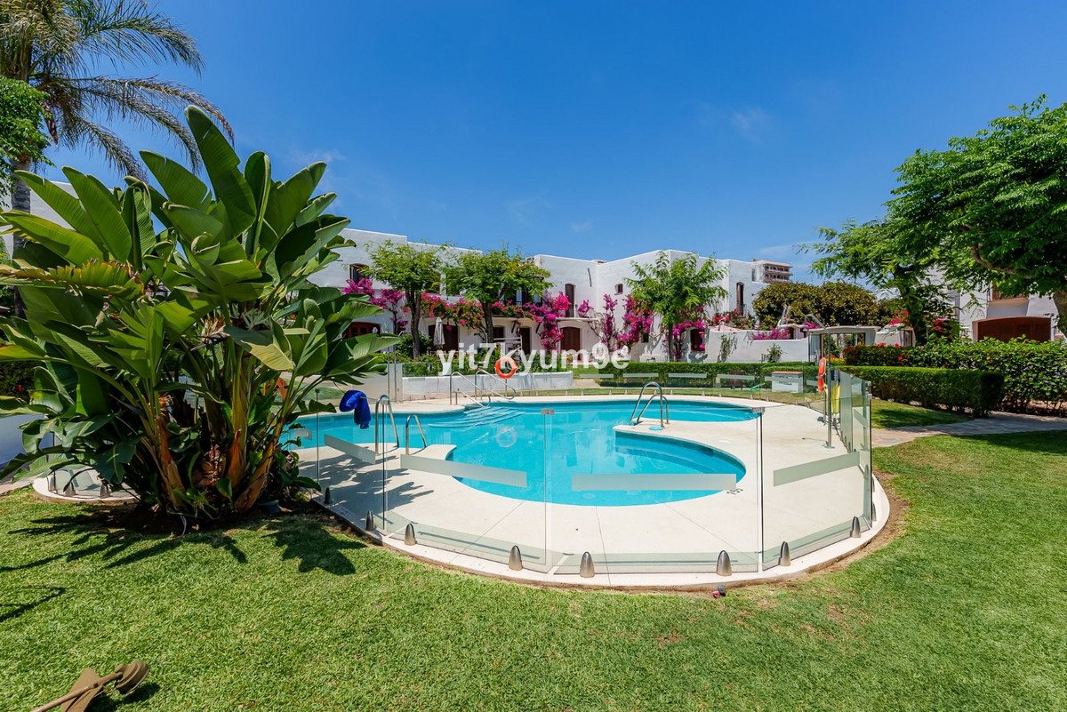 Luxurious swimming pool surrounded by white houses and a tropical garden with vibrant flowers