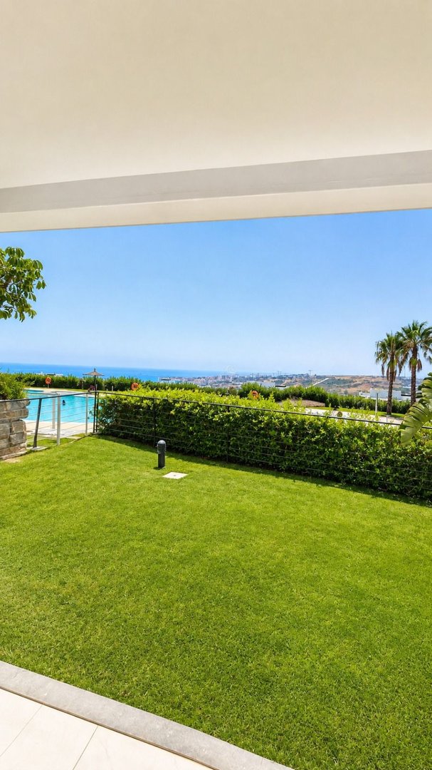 Private garden with a swimming pool and lush green lawn, overlooking the sea and cityscape.