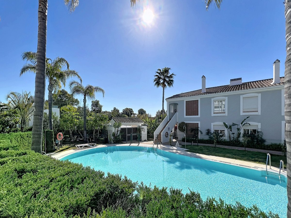 Villa with private pool, palm trees, and lush greenery under a sunny sky.