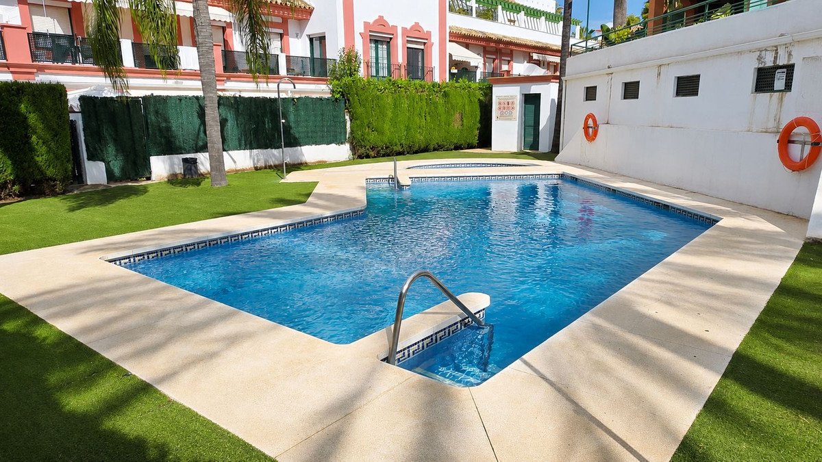 Swimming pool surrounded by a lush green lawn and palm trees