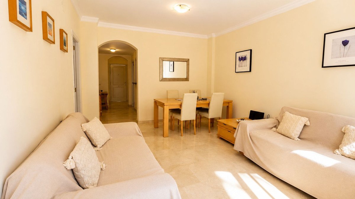 Cozy living room with beige sofas and a dining area with wooden table and chairs