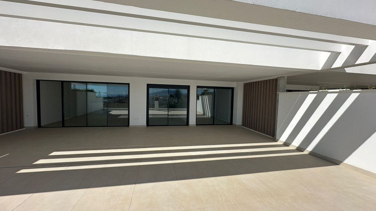Spacious modern terrace with large sliding glass doors offering a view of the landscape.