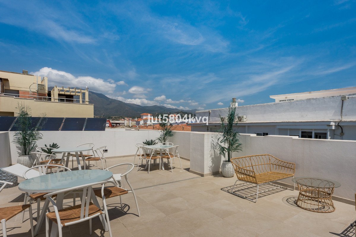 Sunlit rooftop terrace with tables, chairs, and scenic mountain view