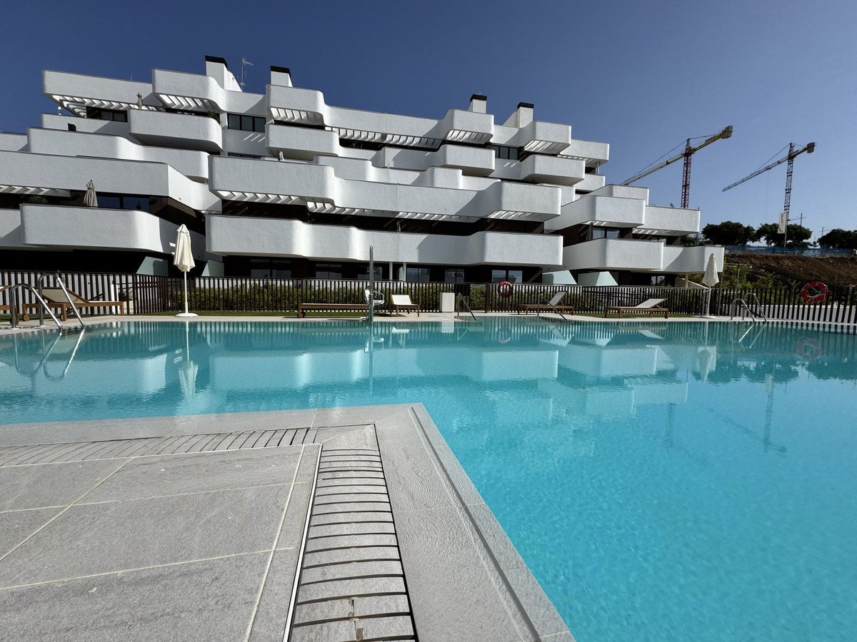 Modern swimming pool in front of a white apartment complex with clear blue water