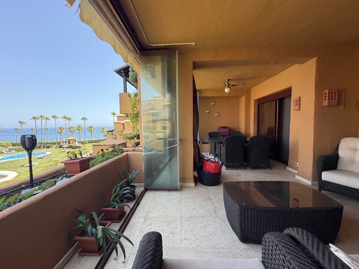 Balcony with sea view and swimming pool, furnished with wicker chairs and table