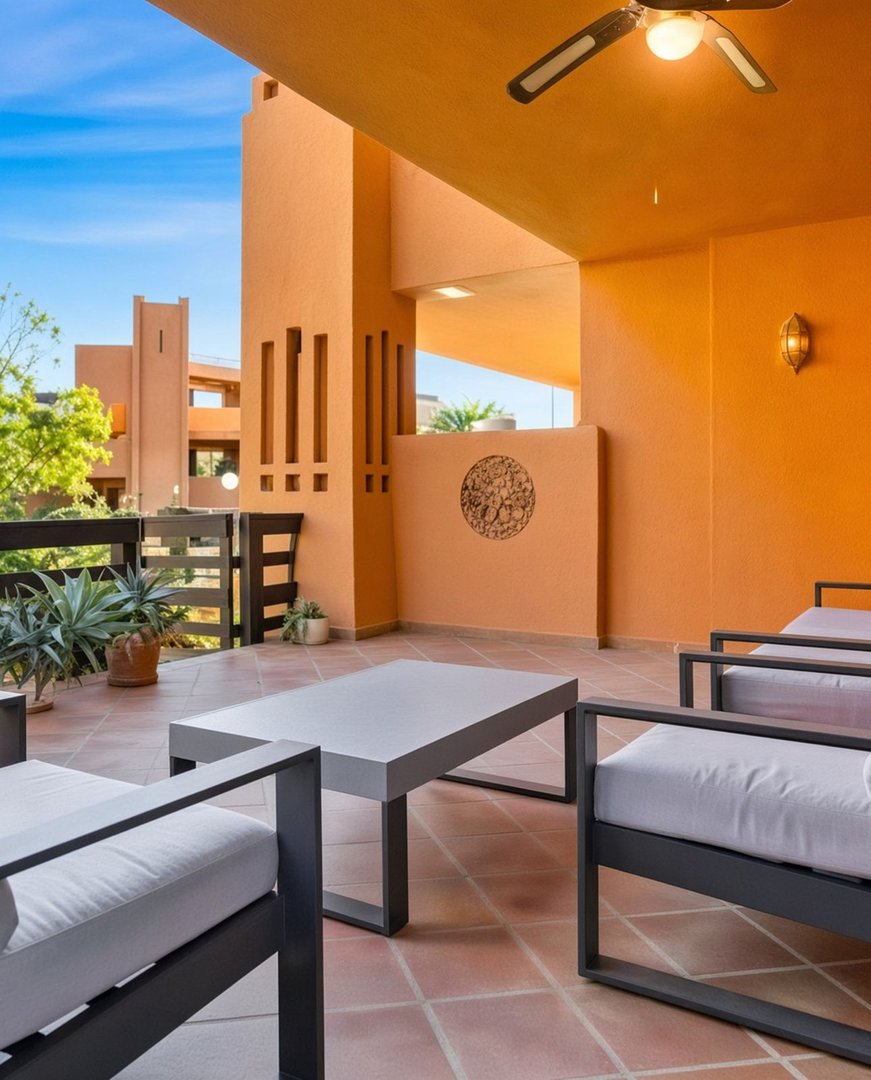 Modern terrace with outdoor seating and coffee table, featuring a ceiling fan and a view of architectural buildings.