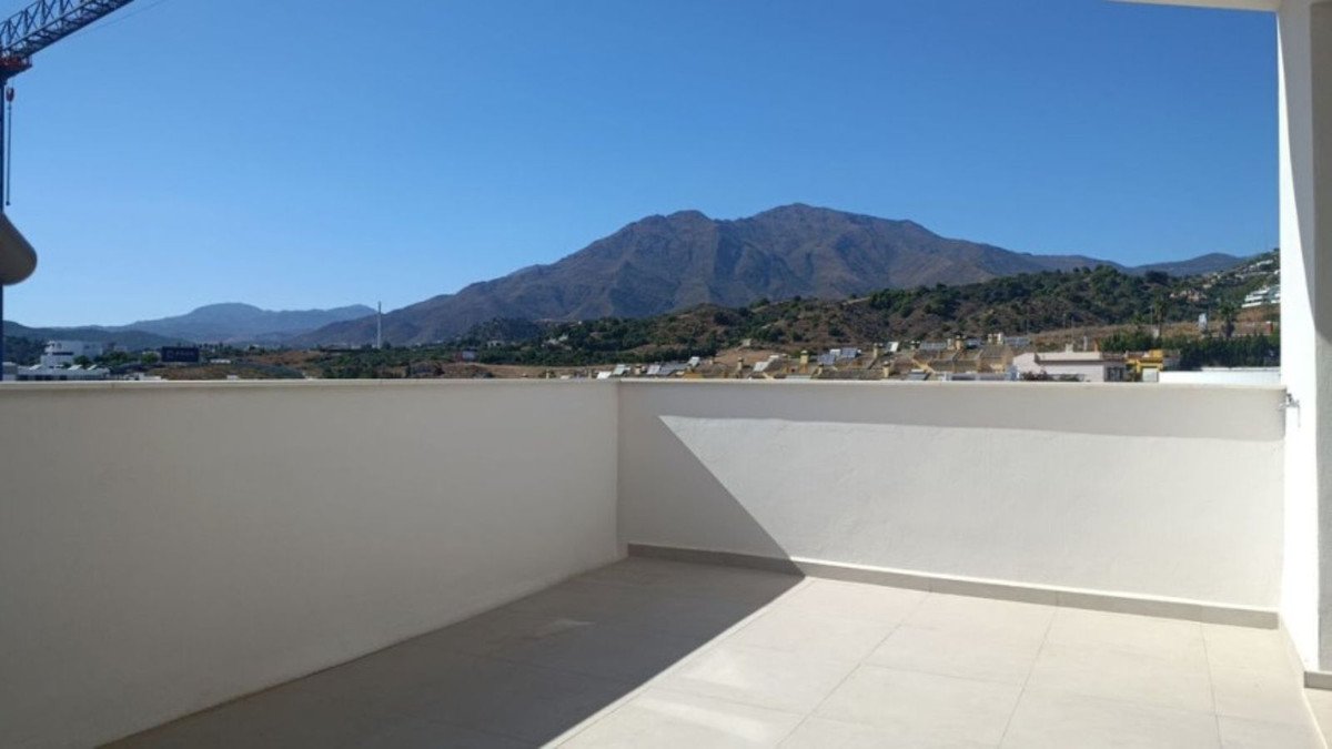 Spacious terrace with a panoramic mountain view and town in the background under a clear blue sky.