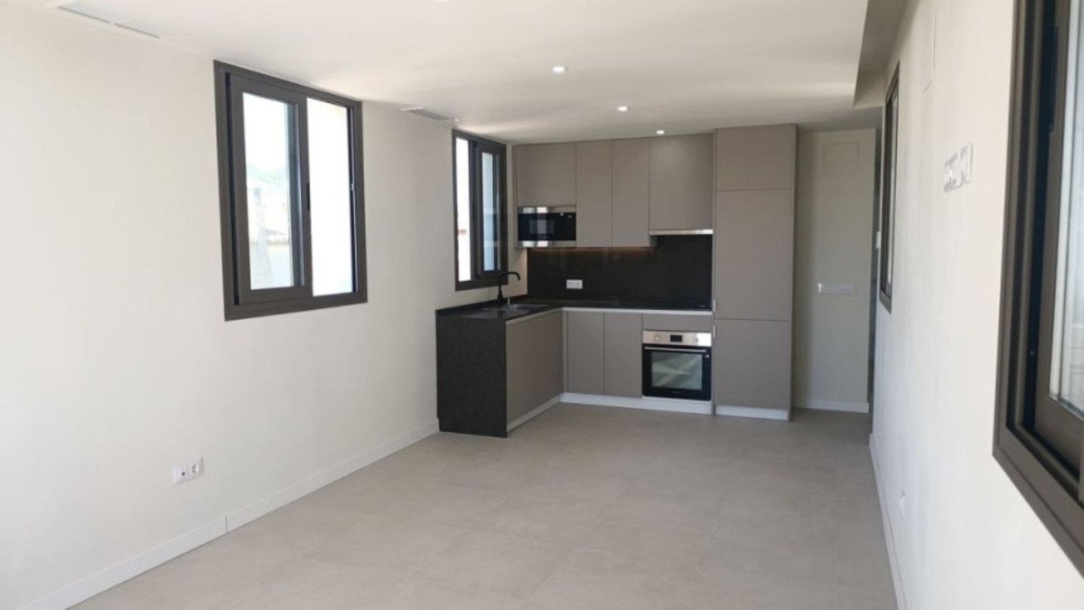 Modern corner kitchen with gray cabinets, black countertop, sink, oven, and microwave. Large windows.