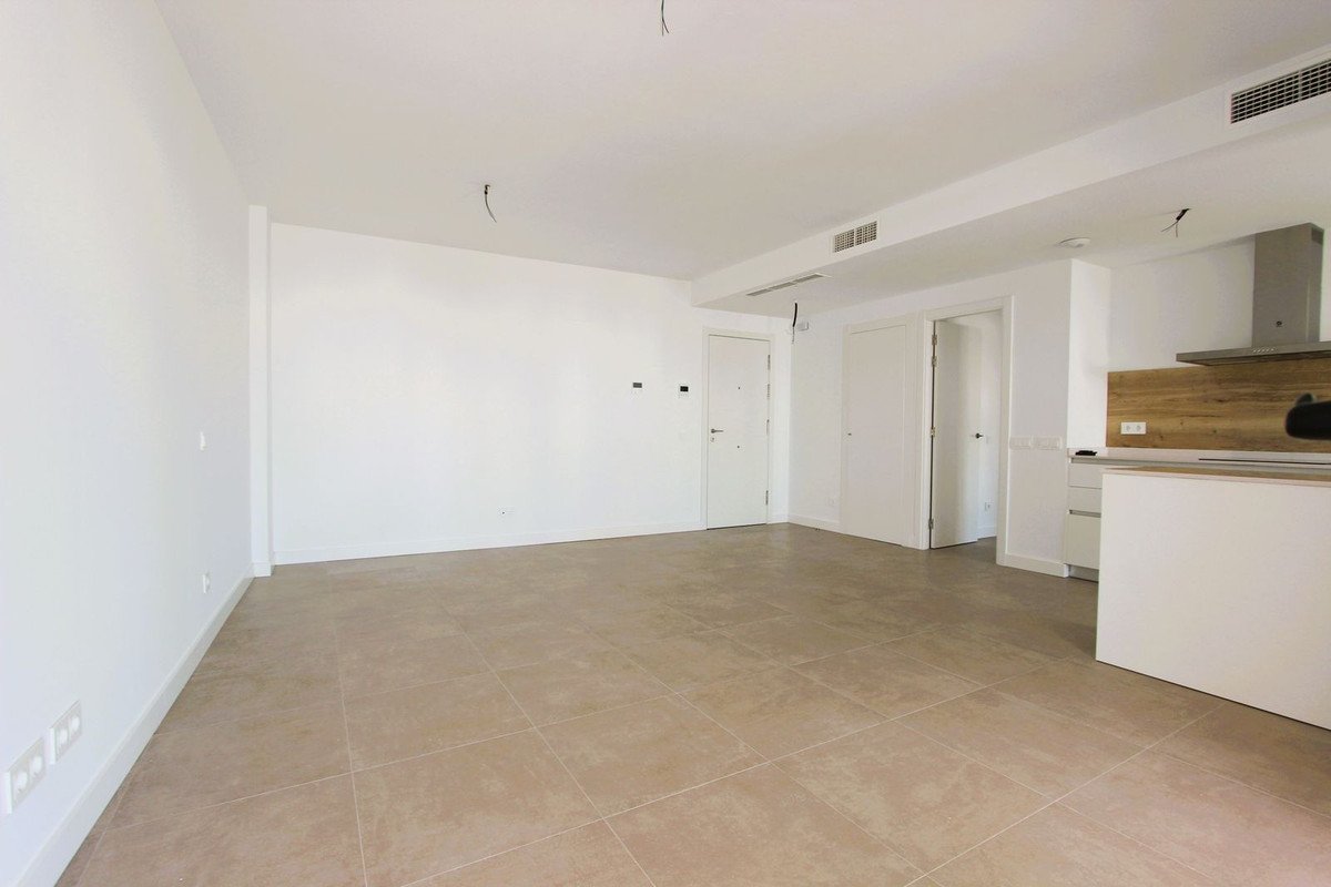 Empty living room with modern kitchen and tiled flooring