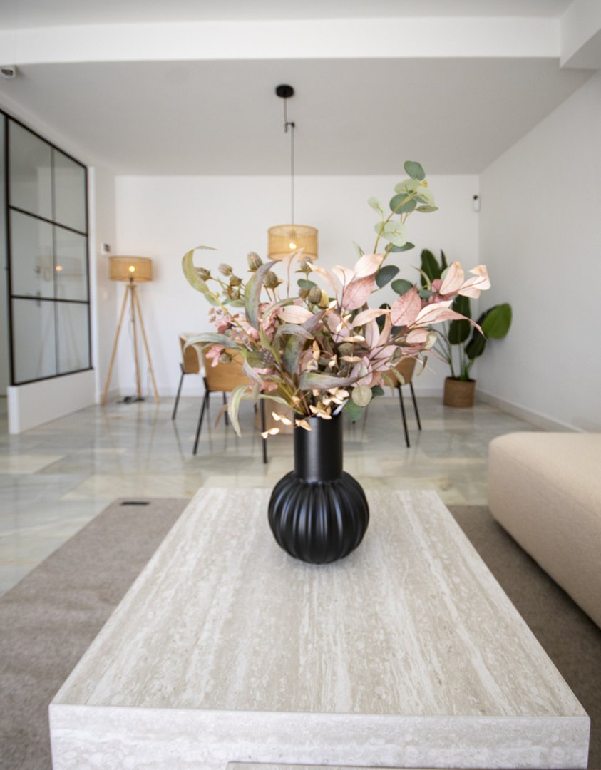 Modern living room featuring a marble table with a black vase holding pink and green plants