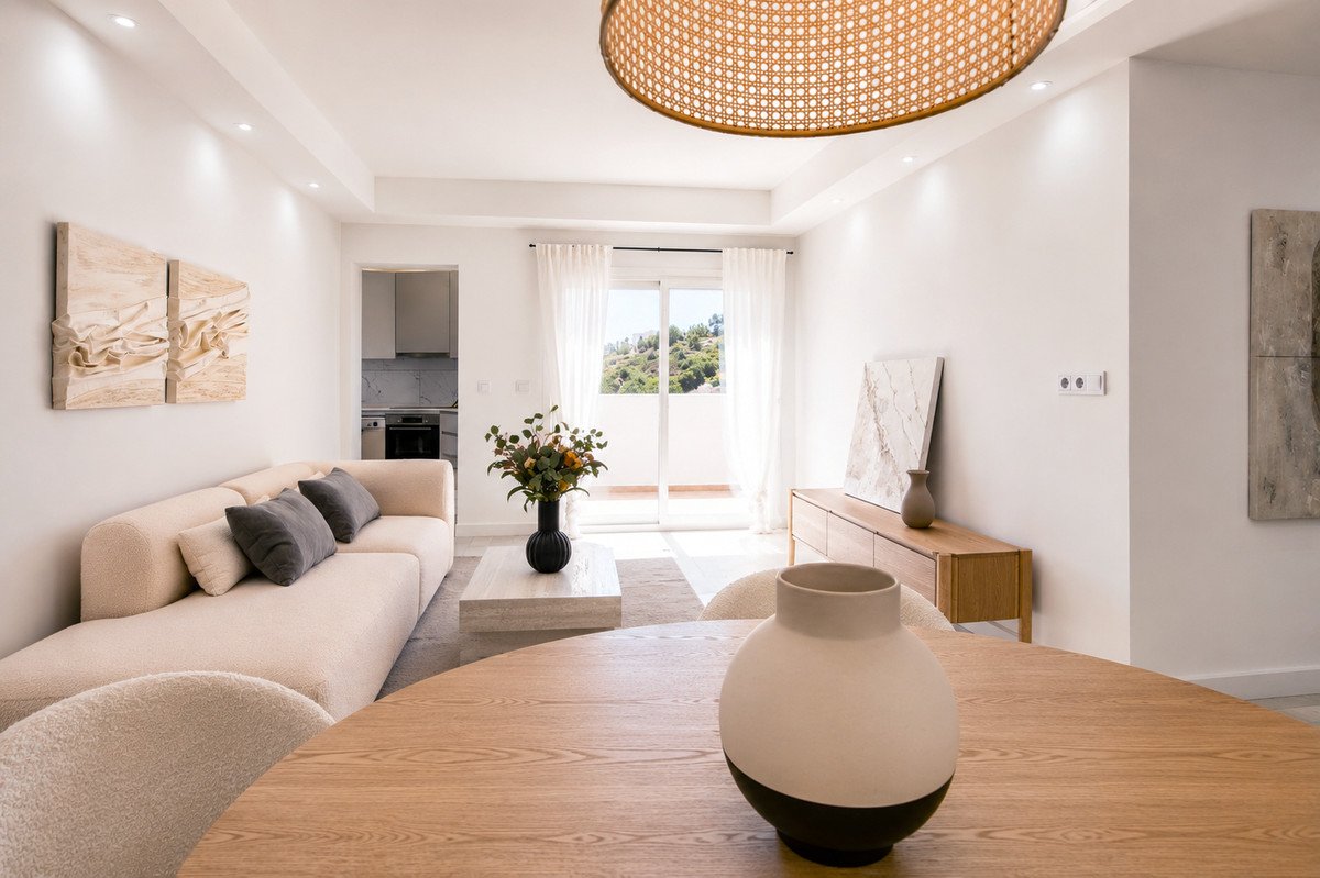 Modern living room featuring a beige sofa, wooden dining table, and large window with scenic view