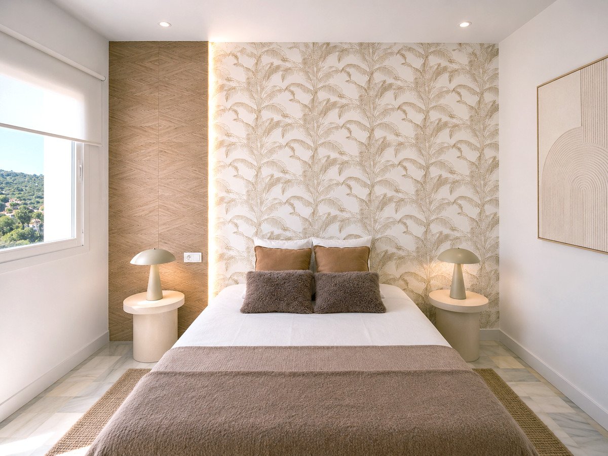 Modern bedroom with tropical wallpaper, wooden accent wall, and a view of green hills through a large window.