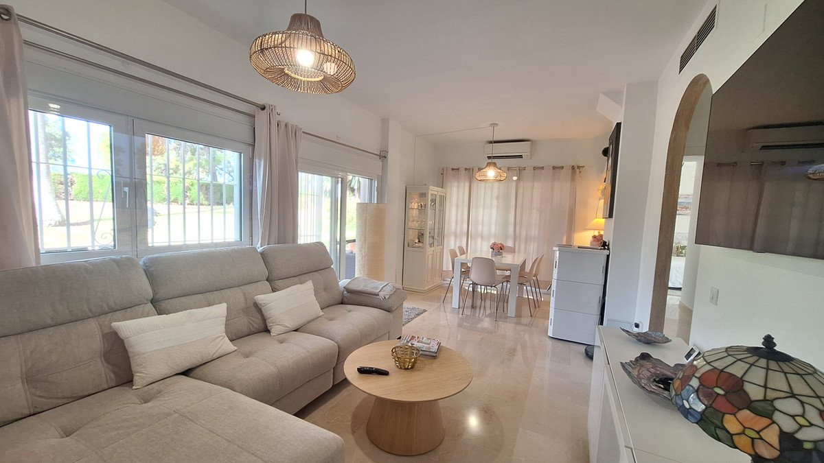 Spacious living and dining area with a large sectional sofa, dining table, and ample natural light from large windows.