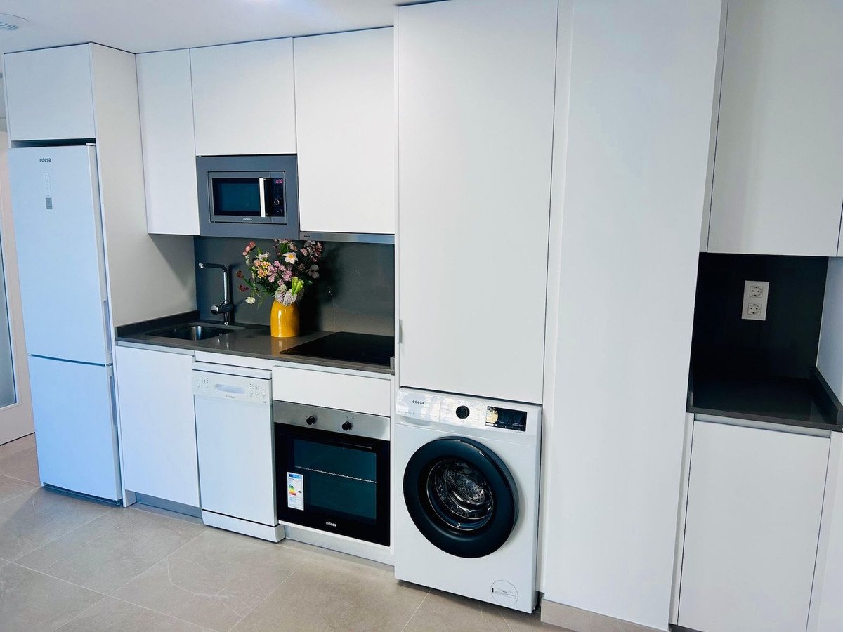 Modern white kitchen with integrated appliances including a refrigerator, oven, dishwasher, microwave, and washing machine.