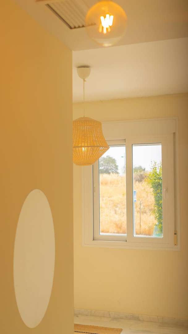 A window with a view of dry vegetation and trees, illuminated by stylish indoor pendant lights.