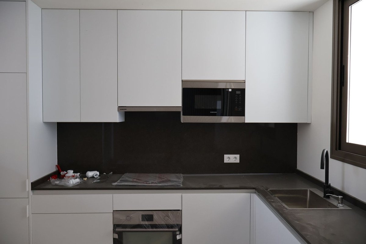 Modern kitchen with white cabinets, black countertop, microwave, and sink.