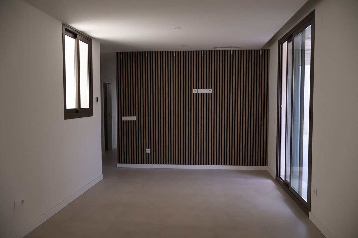 Empty room with wooden slat accent wall, large windows, and sliding glass door.