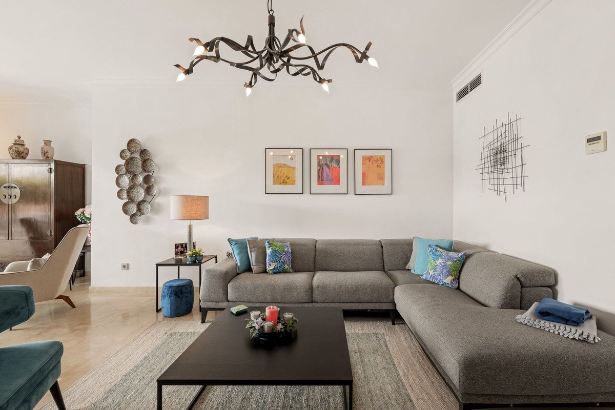 Modern living room with gray sectional sofa, abstract art, and unique chandelier.