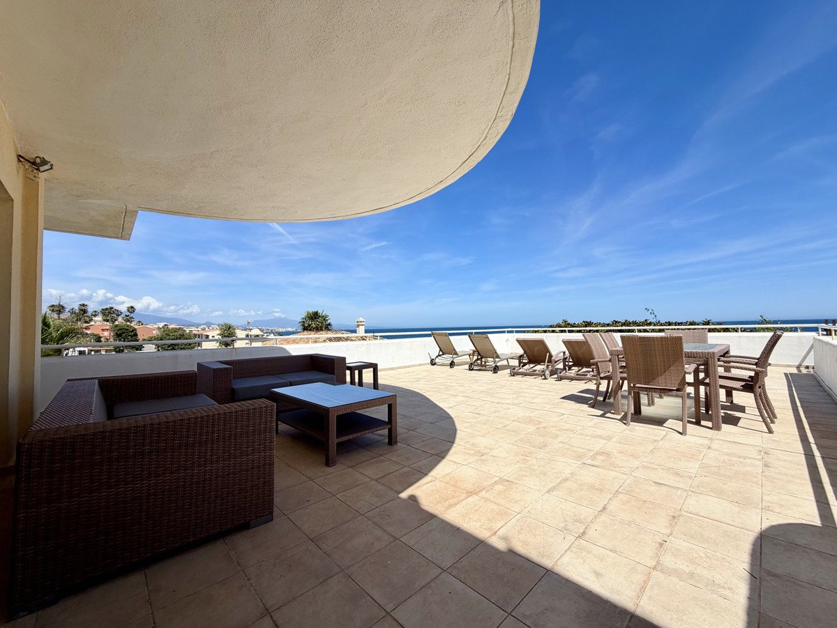 Balcony with sea view, sun loungers, and outdoor furniture under a clear blue sky