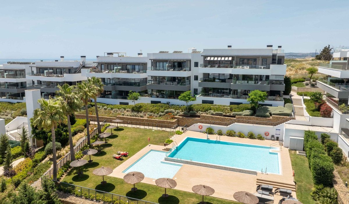 Modern apartment complex with pool, palm trees, and ocean view.