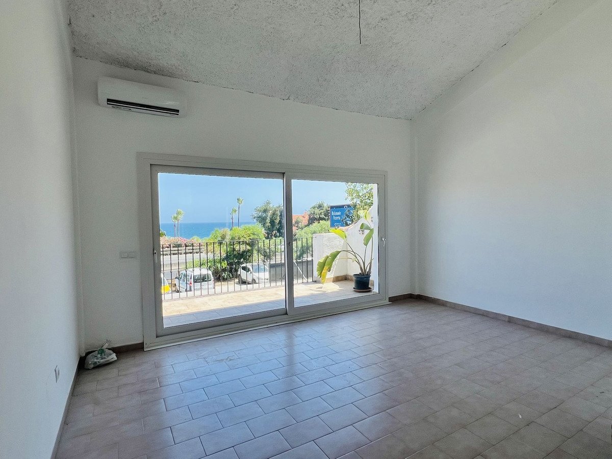 Empty room with tiled floor and ocean view through glass doors