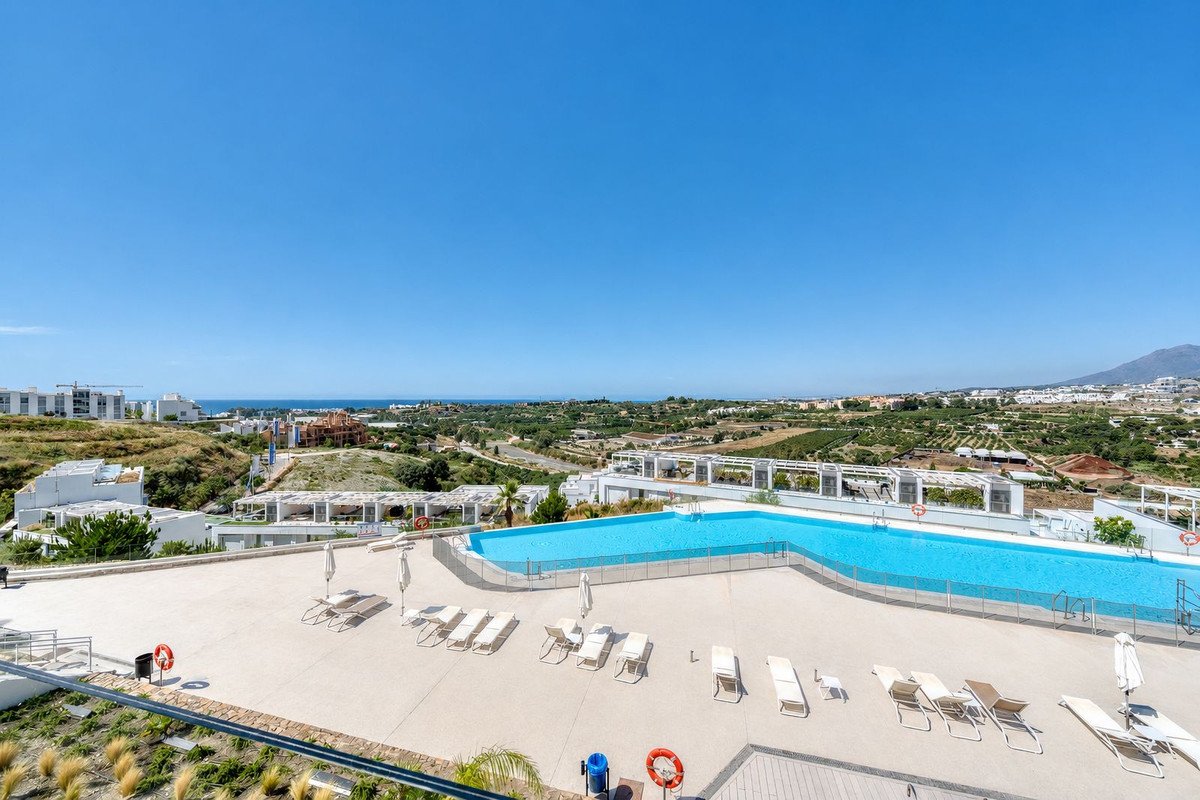 Infinity pool with lounge chairs overlooking the sea and distant mountains