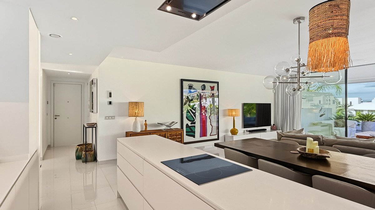 Spacious open-plan living, dining, and kitchen area with modern furniture, artwork, and natural light.