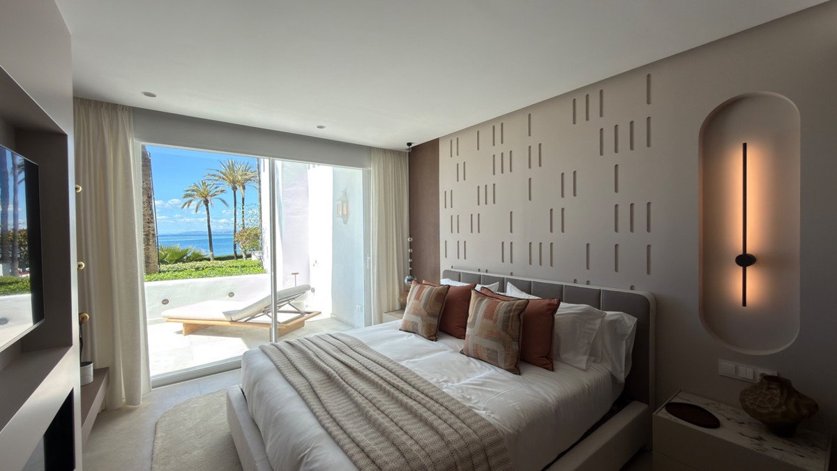 Modern bedroom with large bed, ocean view, and minimalist decor