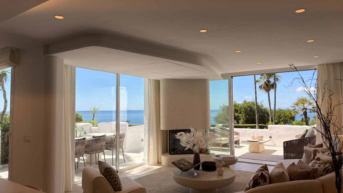 Sunlit living room with large windows overlooking the ocean and palm trees