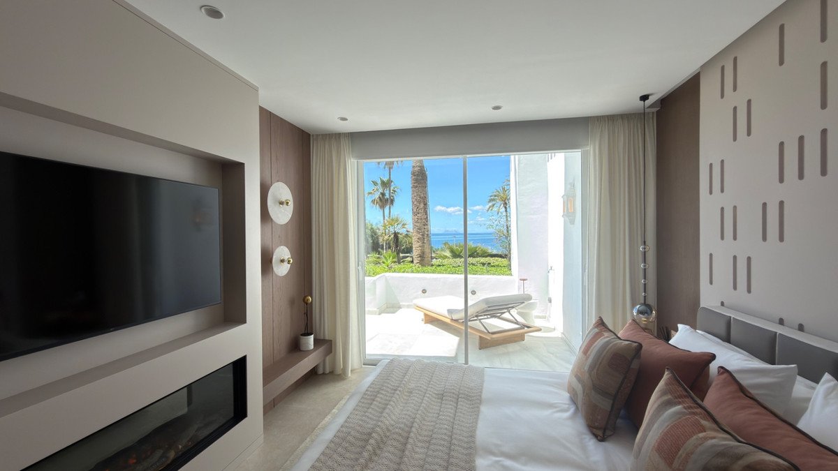 Modern bedroom with large windows overlooking the ocean and a private pool