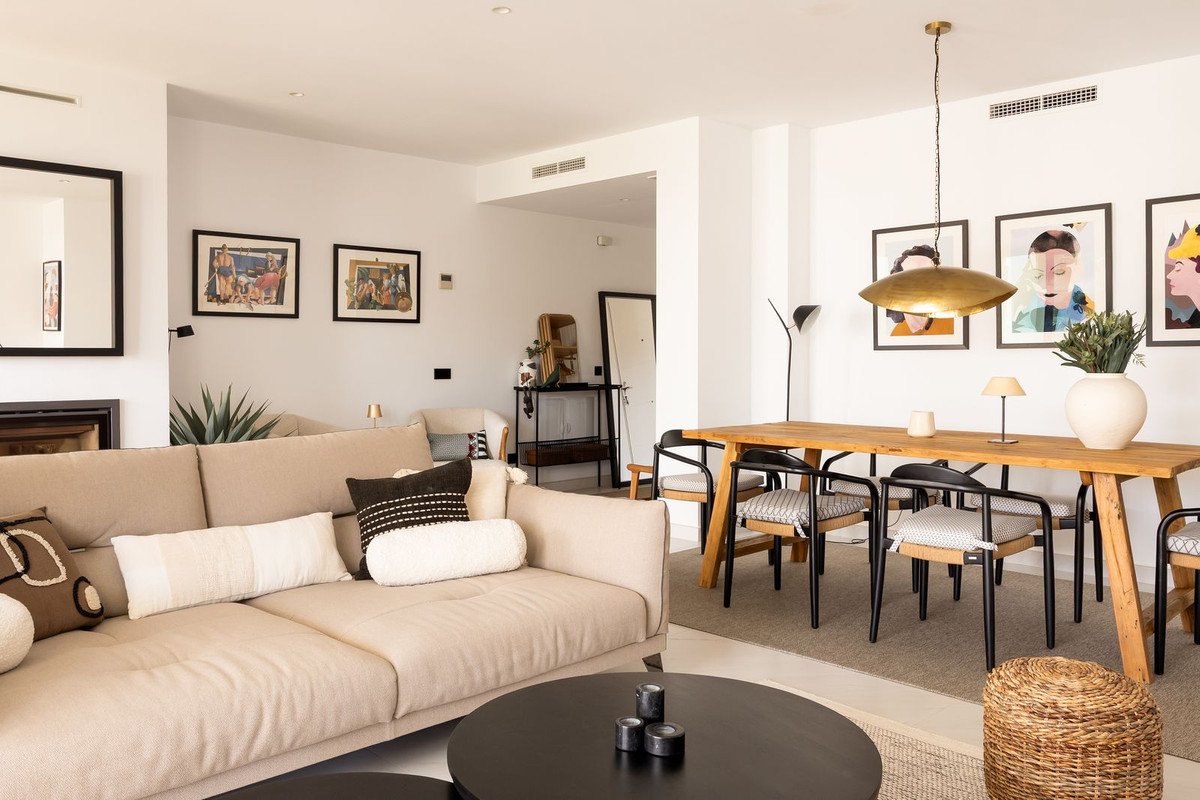 Modern living and dining area with a large sofa, wooden table, chairs, and contemporary art on the walls.