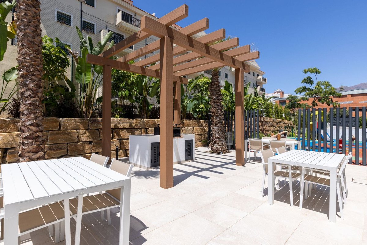 Outdoor patio with white tables, wooden pergola, and pool view.