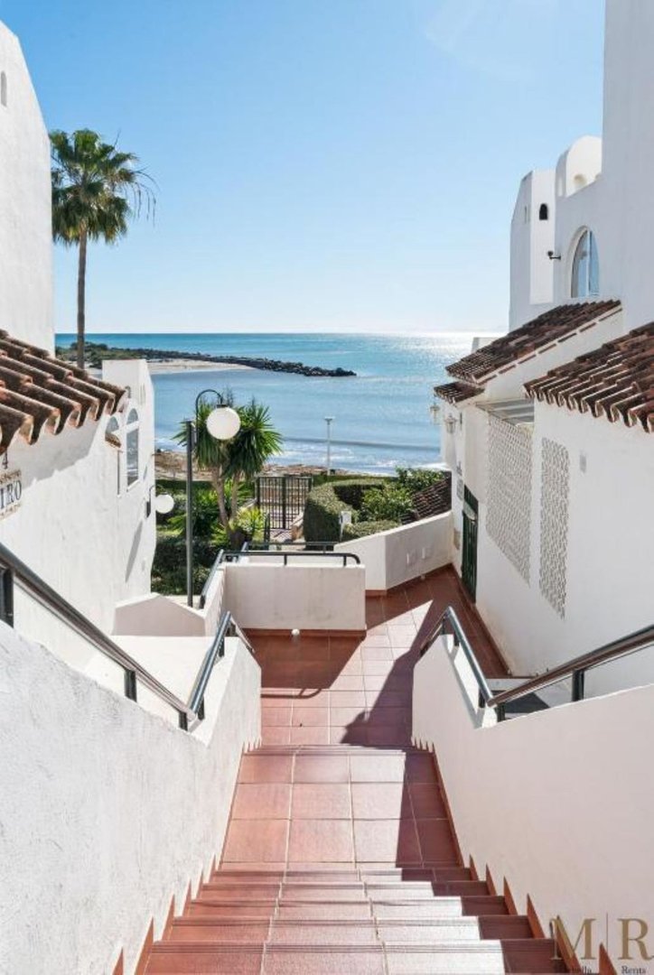 White stairs leading down to a coastal area with ocean view
