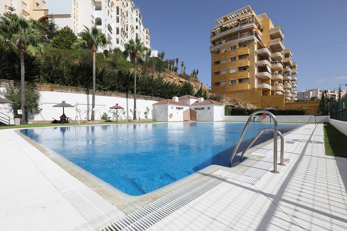 Swimming pool with surrounding luxury apartments and palm trees
