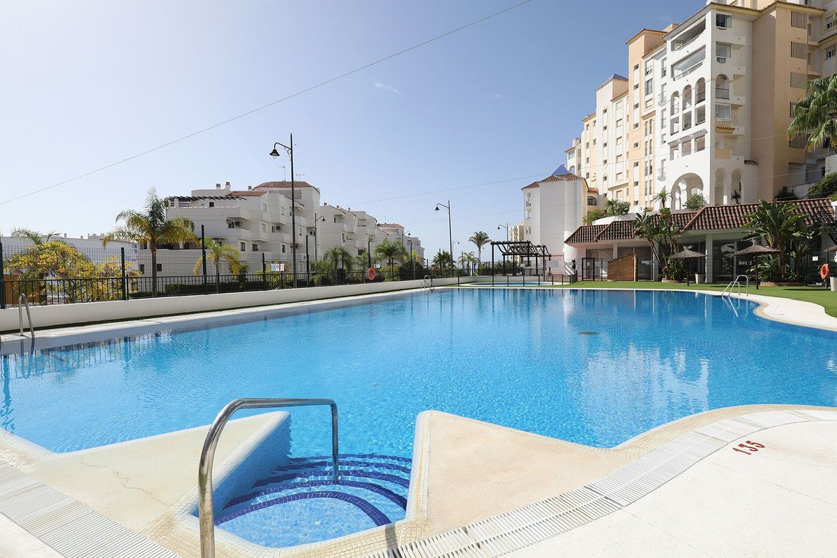 Swimming pool with luxury apartments and palm trees in the background