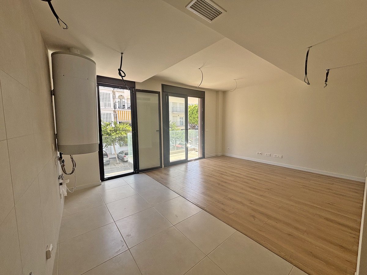 Empty living room with tile and wood floor, large windows and sliding glass doors