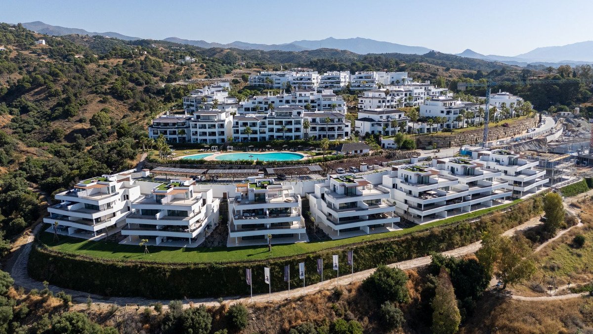 Aerial view of modern white apartment complex with swimming pool and mountain backdrop