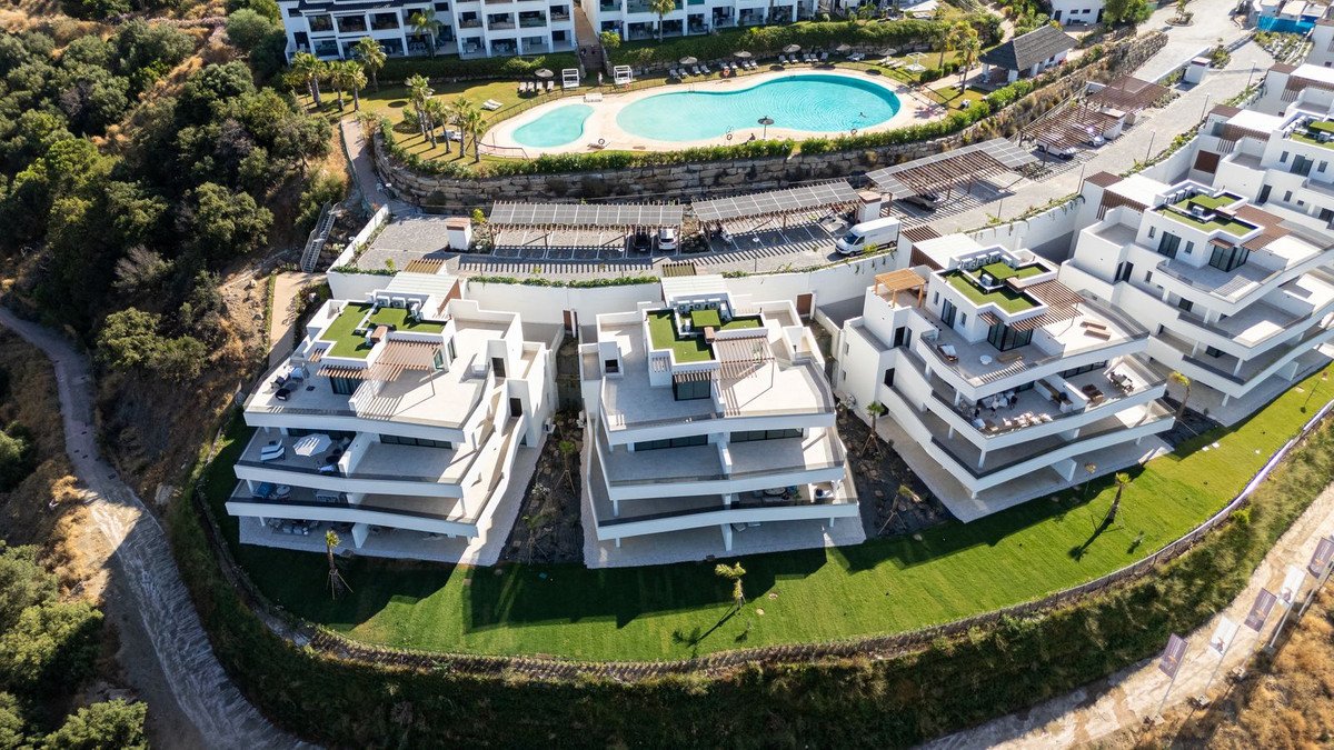 Modern white apartments with a large swimming pool and lush greenery