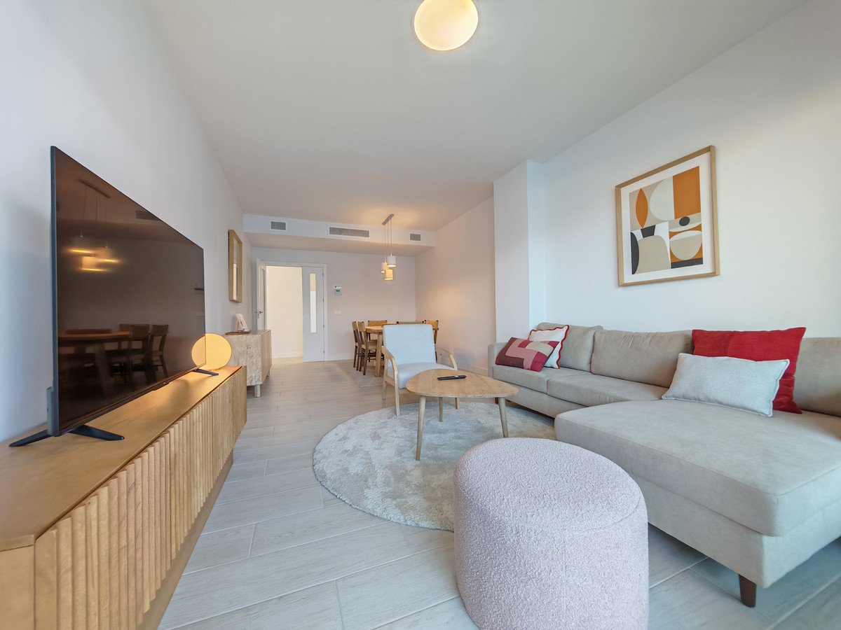 A modern living and dining area with a sectional sofa, coffee table, dining set, and large television.