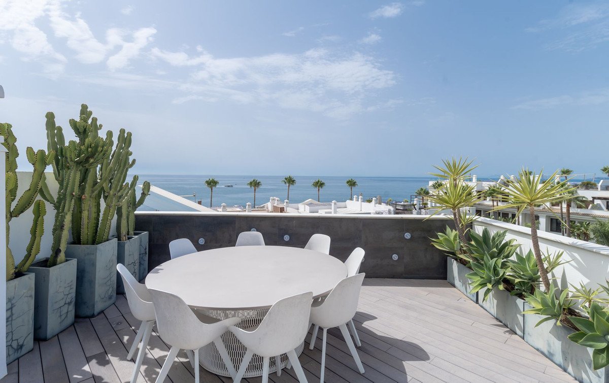White round table with chairs on a terrace overlooking the sea