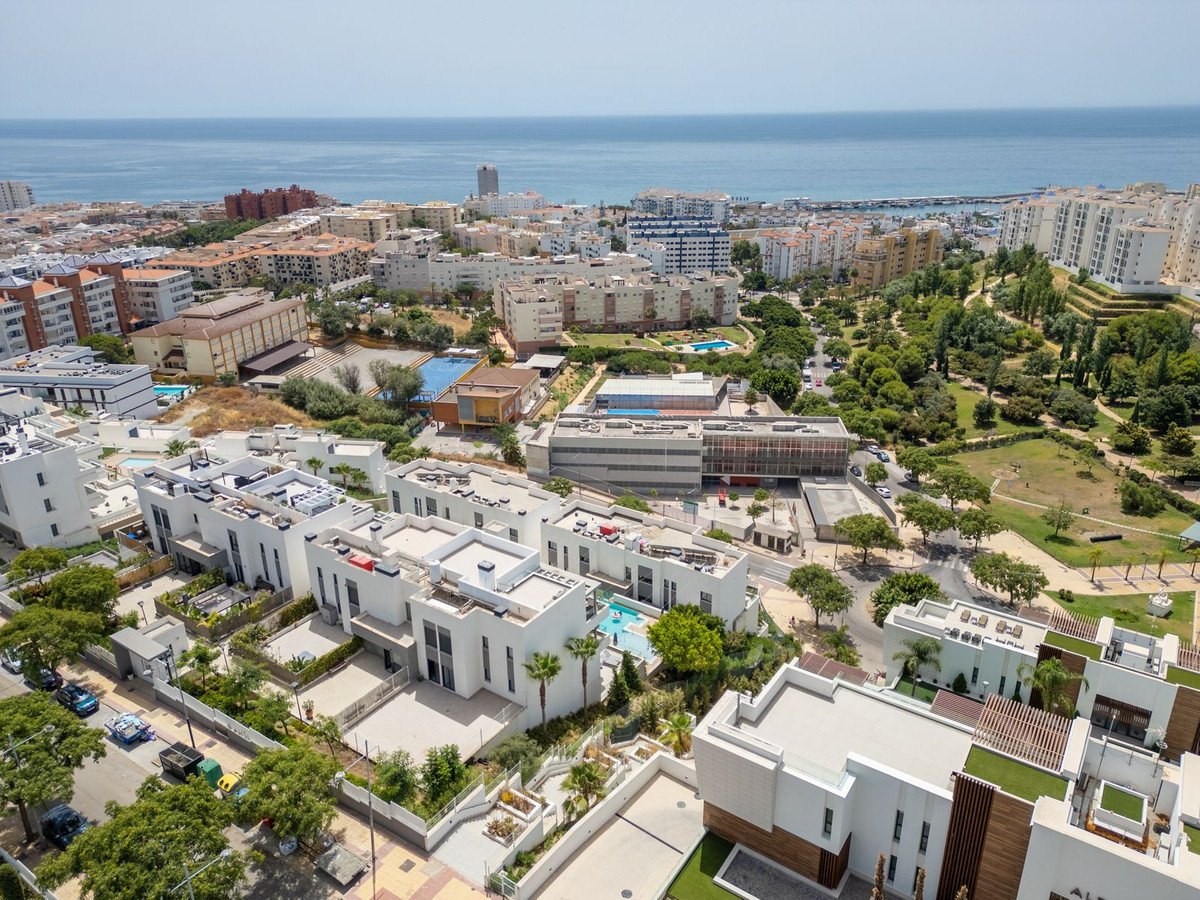 Aerial view of modern white villas with private pools, overlooking the sea and green parkland.