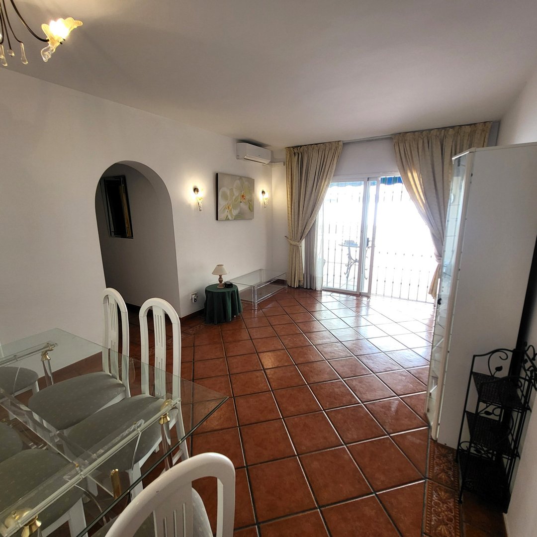 Living and dining area with glass table, leading to a terrace with natural light and outdoor views.
