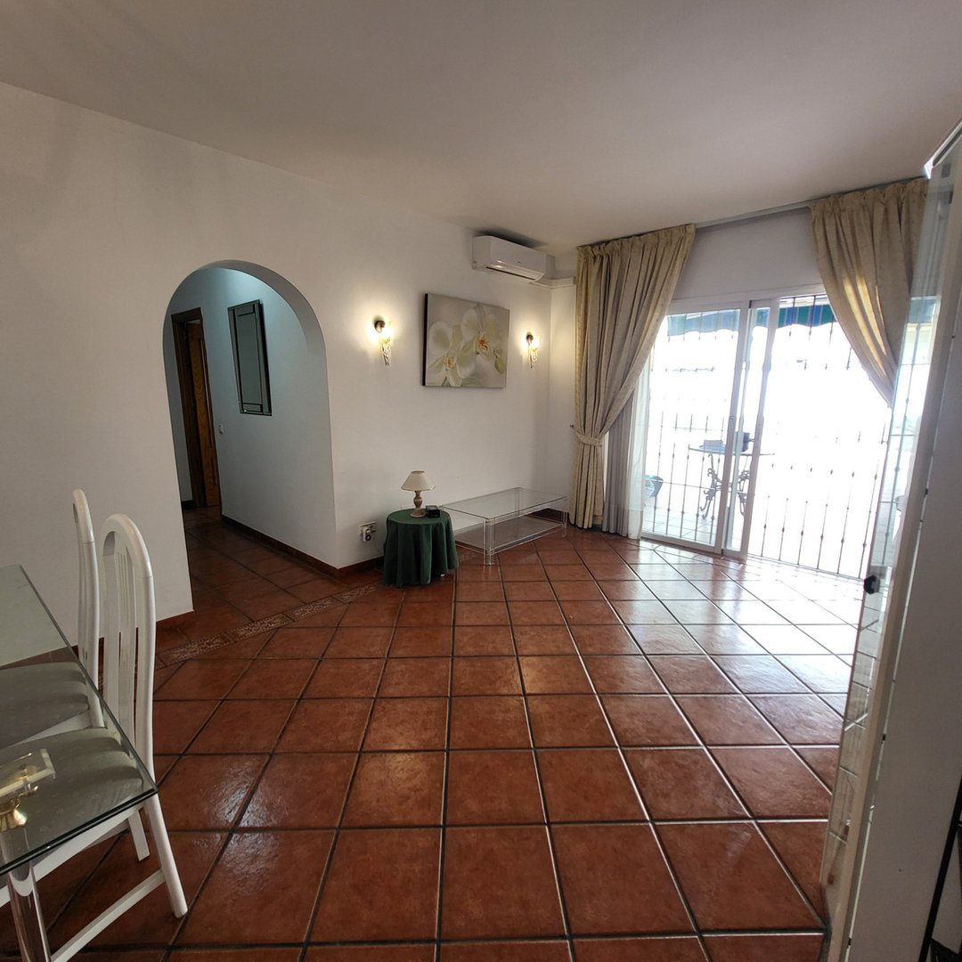 Spacious living room with terracotta tiles, modern furniture, and sliding glass doors leading to an outdoor balcony.