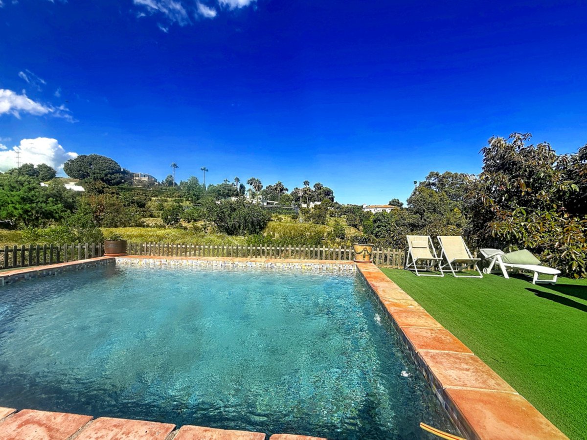 Swimming pool with lounge chairs and green lawn overlooking a scenic landscape