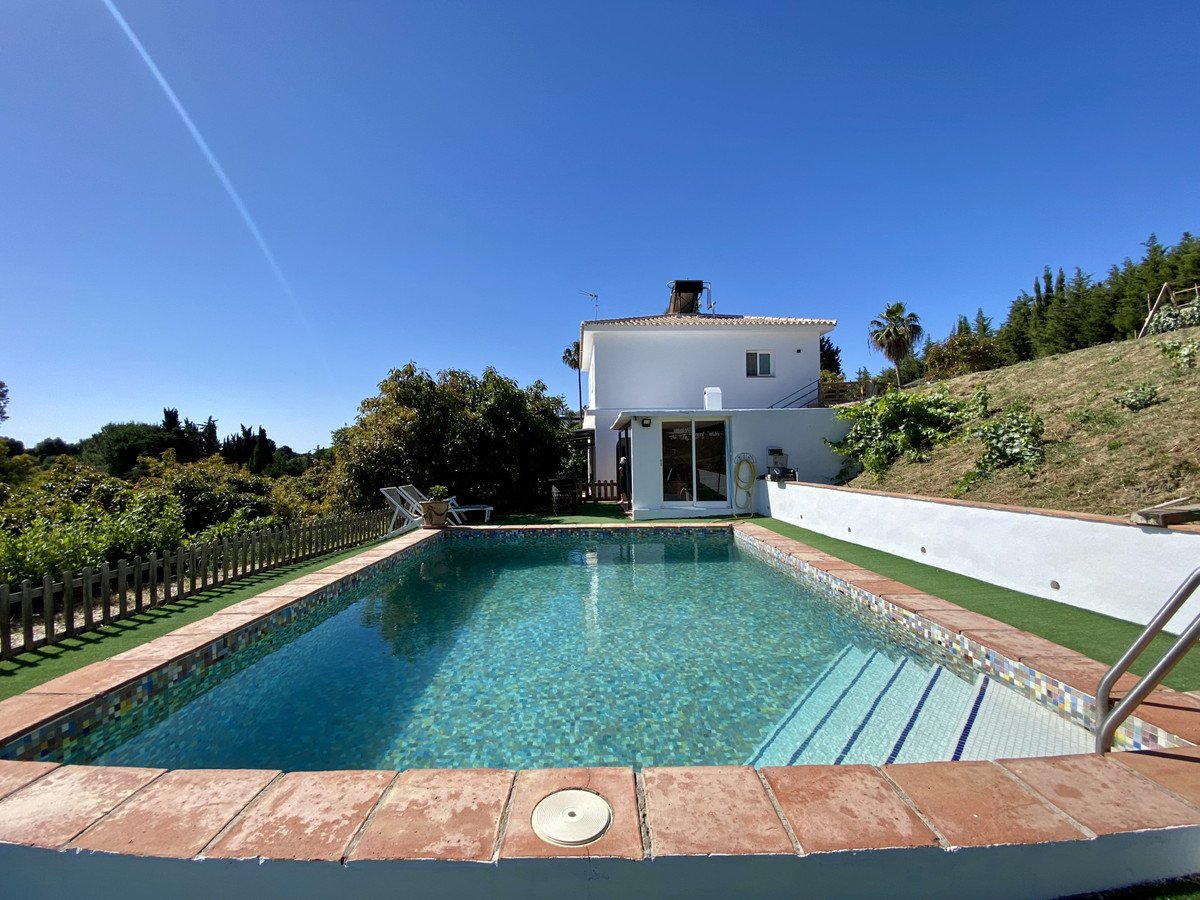 Swimming pool outside a white house with clear blue sky and greenery